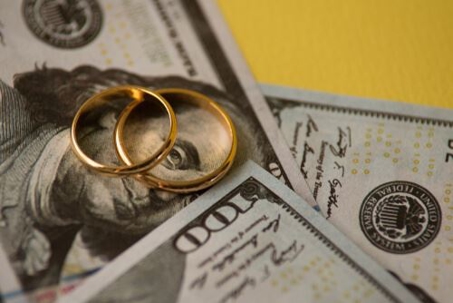 2 gold wedding bands on top of cash ($100 bills) to represent alimony