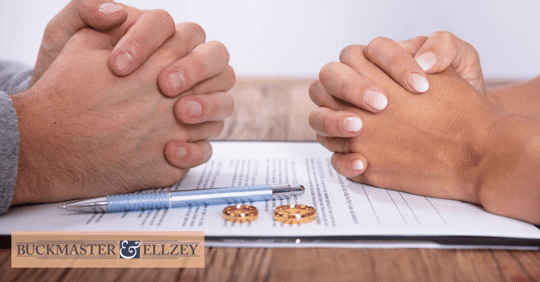 Two pairs of clasped hands on top of divorce papers